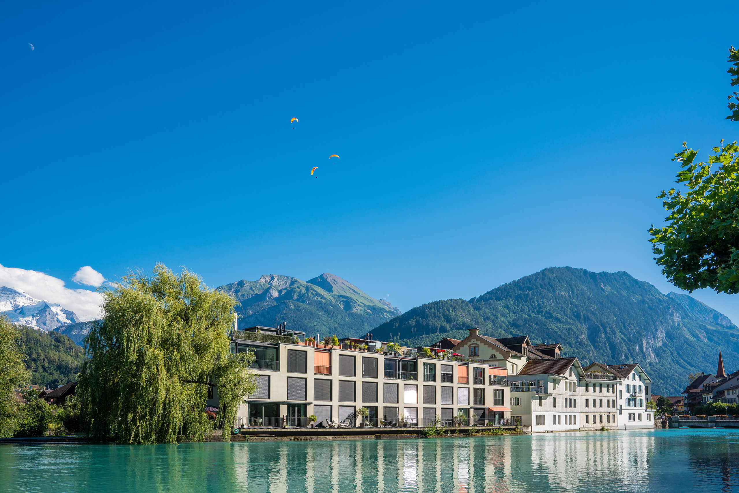 Interlaken an der Aare mit Paraglidern im Hintergrund